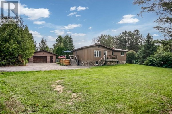 Wide shot of the property exterior featuring a brown bungalow, detached garage, and expansive green lawn. - 2 Adam, Lively