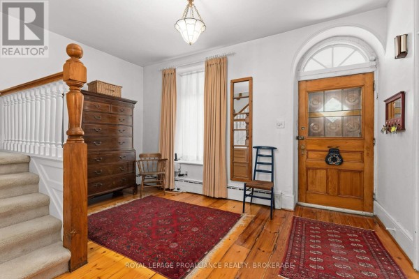 Interior foyer with a wooden door, staircase, two rugs, and antique furniture. - 2 Alwington Avenue, Kingston