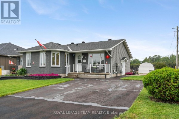 Side exterior view of a grey bungalow with a driveway and green lawn. - 2 Billings Avenue W, South Dundas