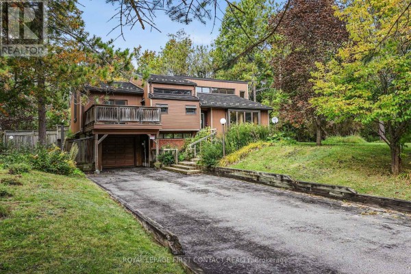 Daytime view of the two-story house with brown siding and a sloped driveway. - 2 Briarwood Court, Springwater