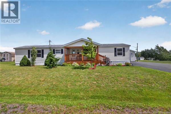 Side view of a light-colored house with a wooden deck and attached garage with a white door. - 2 Bur Oak Street, Moncton