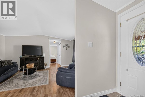 Living room interior with a television, couches, coffee table, and wood-look flooring. - 2 Bur Oak Street, Moncton