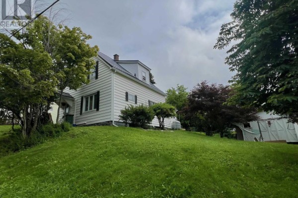 View of the white siding house with a sloped green lawn and mature trees. - 2 Central Avenue, Trenton