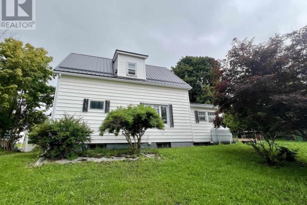 Side view of the white siding house with a dark metal roof and green bushes. - 2 Central Avenue, Trenton