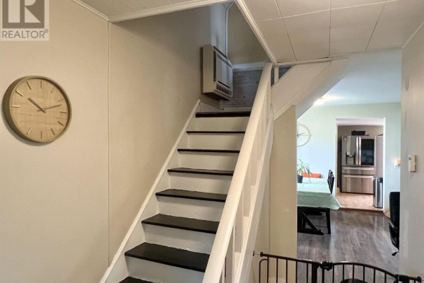 Interior view of a staircase with white railings and dark treads, leading to a kitchen. - 2 Central Avenue, Trenton