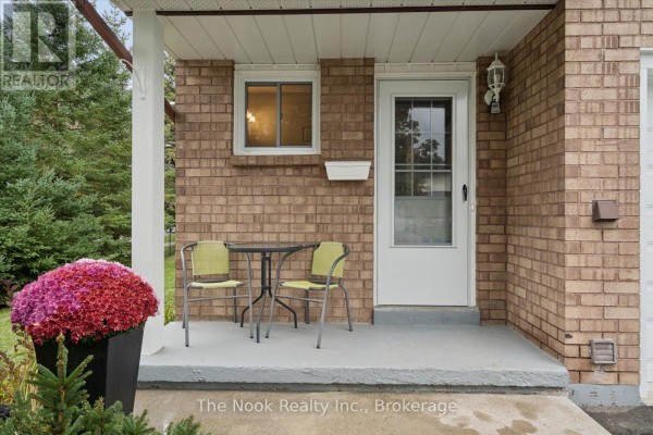 Covered front porch with brick facade, two chairs, a small table, and a white door. - 2 Century Boulevard, Cavan Monaghan