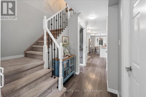 Interior foyer with carpeted stairs, dark wood floor, and a blue console table. - 2 Century Boulevard, Cavan Monaghan