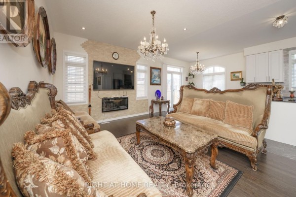 Living room with ornate sofas, marble coffee table, rug, and fireplace with TV. - 2 Cliff Thompson Court, Georgina