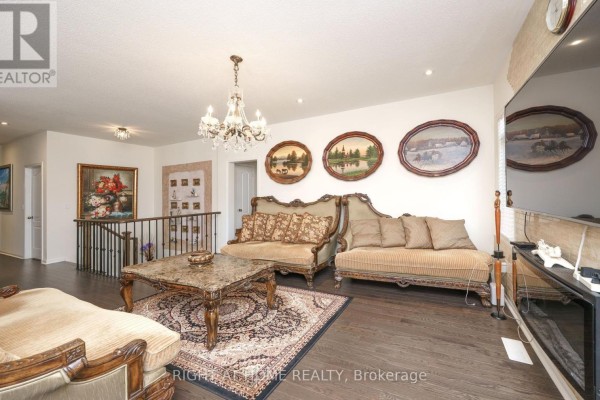 Living room with dark hardwood floors, seating, artwork, and a television console. - 2 Cliff Thompson Court, Georgina