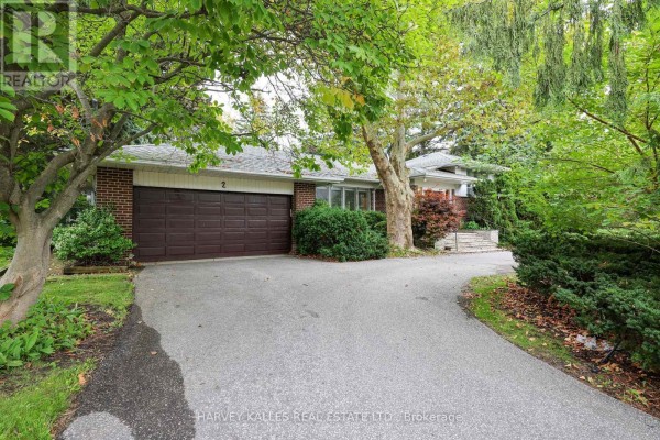 Side exterior of the house showing a double garage door and driveway. - 2 Clovestone Road, Toronto