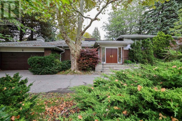 View of the house facade with red brick, large windows, and abundant greenery. - 2 Clovestone Road, Toronto
