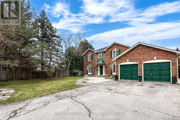 Side exterior view of a large red brick house with a well-kept lawn and a two-car garage. - 2 Craigleith Crescent, Richmond Hill