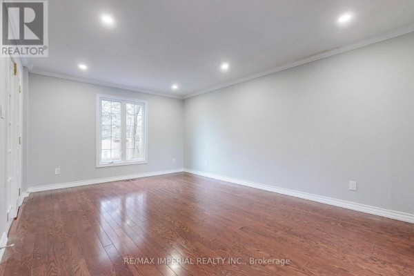 Interior view of an empty room with dark hardwood floors, light grey walls, and recessed lighting. - 2 Craigleith Crescent, Richmond Hill