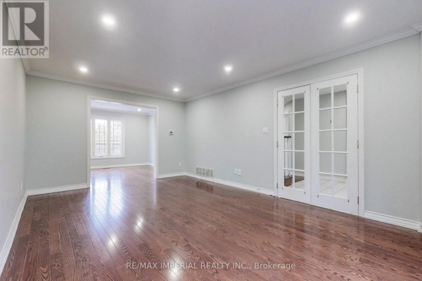 Interior view of an empty room with hardwood floors, light grey walls, and glass-paned double doors. - 2 Craigleith Crescent, Richmond Hill