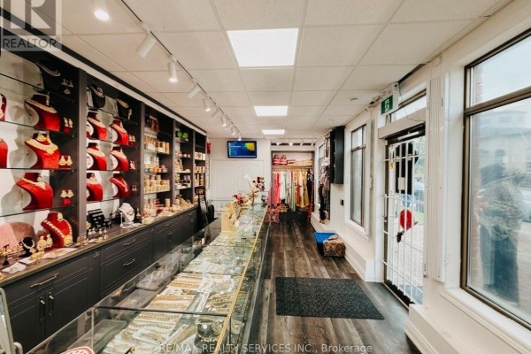 View of a jewelry store interior showing display cases, shelves, clothing racks, and a side entrance. - 2 Davenfield Circle, Brampton