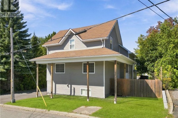 Front corner view of a grey house with a covered porch and wooden fence. - 2 Evans Road, Copper Cliff