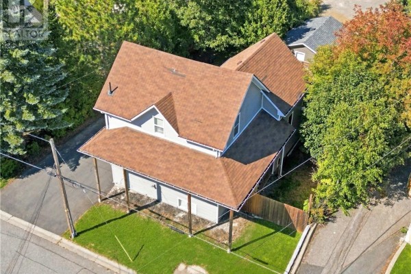 Aerial view of the back of a grey house with a brown roof and surrounding trees. - 2 Evans Road, Copper Cliff