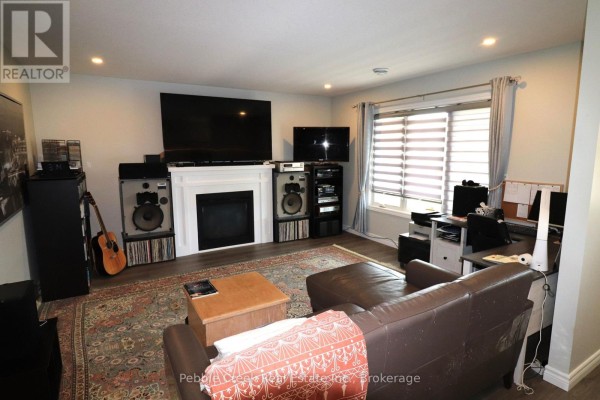 Living room with a fireplace, entertainment center, large sectional sofa, and desk area. - 2 Highview Street, Ashfield Colborne Wawanosh