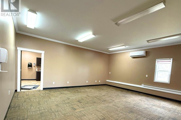 Spacious office area with tan walls, beige carpet, and fluorescent lighting. Includes an air conditioning unit and window. - 2 Industrial Park, Springdale