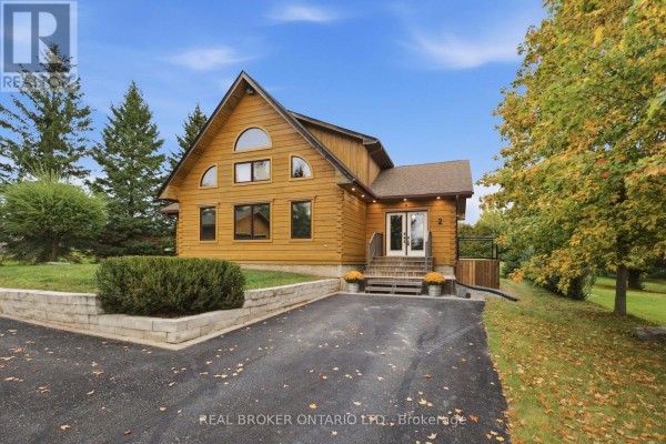 Front exterior of a wood-sided house with a paved driveway and landscaping. - 2 Limosano Street, Scugog