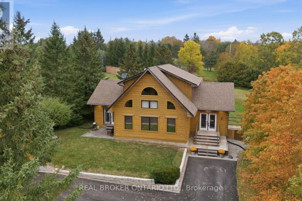 Front view of a large wooden house with trees and fall colors in the background. - 2 Limosano Street, Scugog