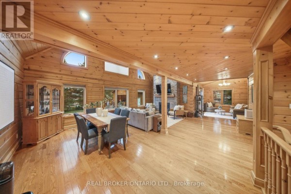 Open concept living and dining area with wood paneling, hardwood floors, and fireplace. - 2 Limosano Street, Scugog