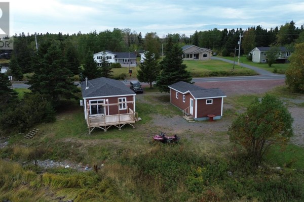 Aerial view of a red house with a deck, a small detached red shed, and a driveway with a vehicle. - 2 Main Street, Northern Arm