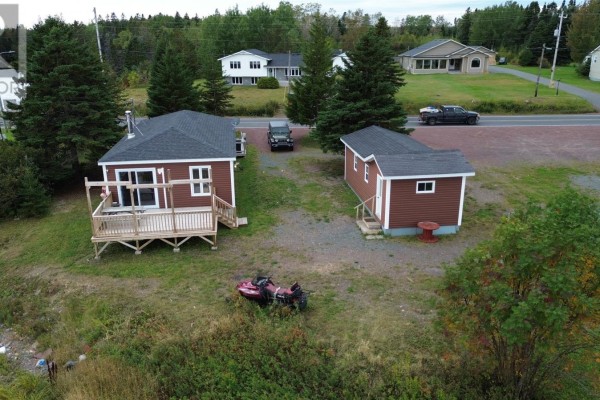 Aerial view of the red house and detached shed on a grassy lot, with a vehicle and ATV visible. - 2 Main Street, Northern Arm