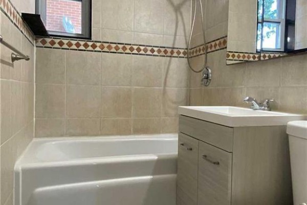 Small bathroom with a bathtub, vanity, sink, toilet, and tiled walls. - 2 Mendip Crescent, Toronto