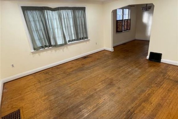 Living room with hardwood floors, cream walls, and a large window with teal curtains. - 2 Menzie Avenue Unit# Upper, Guelph