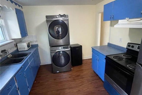 Kitchen with blue cabinets, a double sink, stacked washer and dryer, and a microwave. - 2 Menzie Avenue Unit# Upper, Guelph