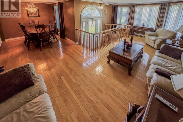 Open-concept living and dining area with hardwood floors, plush sofas, and a wooden dining set. - 2 Millers Avenue, Roberts Arm