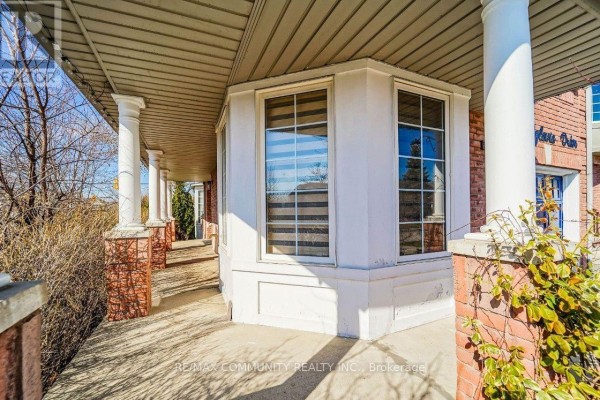 Close-up of a covered porch with white columns and a bay window on a brick house. - 2 Oglevie Drive, Whitby