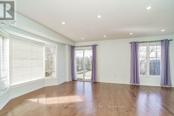 Living room with hardwood floors, bay window, sliding glass doors, and purple curtains. - 2 Oglevie Drive, Whitby