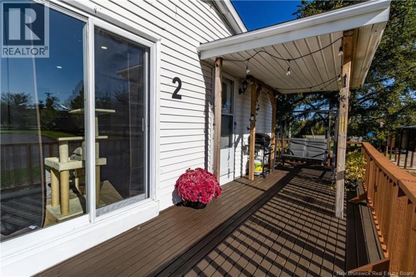 Close-up of the wooden deck and porch, showing a sliding glass door and outdoor seating. - 2 Orchard Crescent, Picadilly