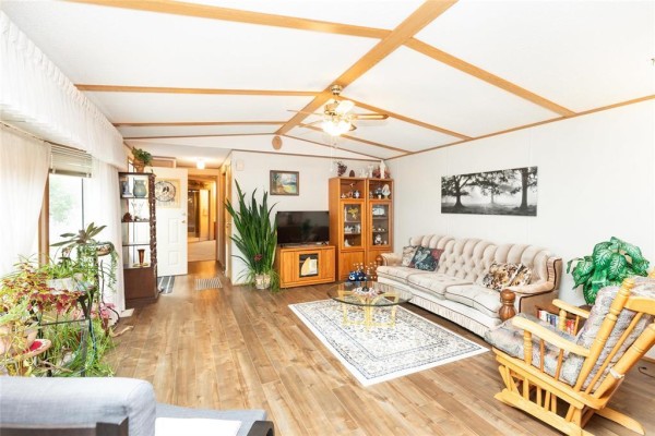 Living room with wood-look flooring, a beige sofa, armchair, and glass coffee table. - 2 Paradise Drive, Ste Anne