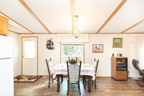 Dining area with a table set for four, a chandelier, and a white refrigerator. - 2 Paradise Drive, Ste Anne