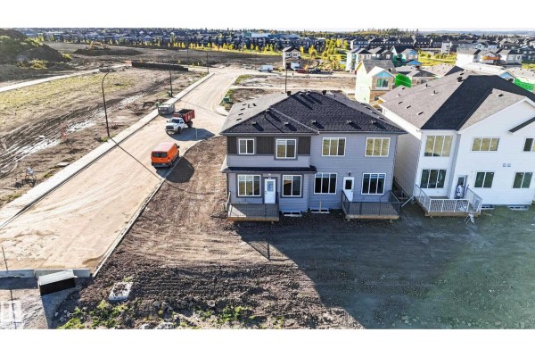 Aerial view of the back of the duplex with grey siding, two back decks, and a surrounding construction site. - 2 Parker Ln, Spruce Grove