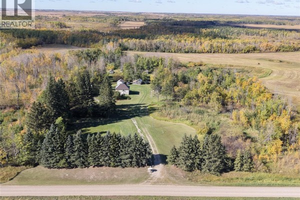 Aerial view of a house and outbuildings nestled amongst trees, with a long driveway leading from the road. - 2 Quarters Mixed Use Land & Yard Site Near Sheho, Foam Lake Rm No  276