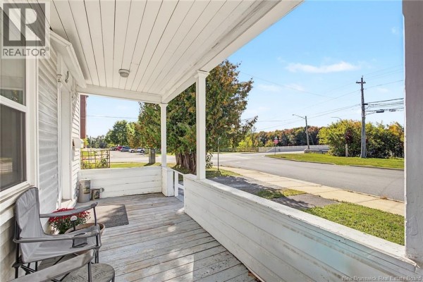 View from the covered porch looking down the street, showing trees and utility poles. - 2 River Street, Fredericton