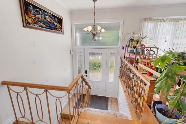 Interior view of the foyer with a glass-paneled front door and a wooden staircase railing. - 2 Rue De Foix, Gatineau