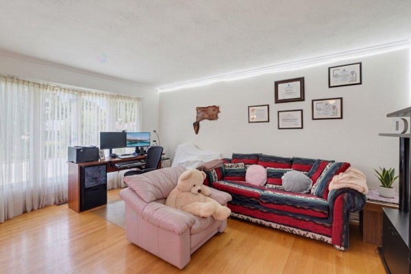 Living area with light wood floors, a pink armchair, a striped sofa, and framed certificates on the wall. - 2 Rue De Foix, Gatineau