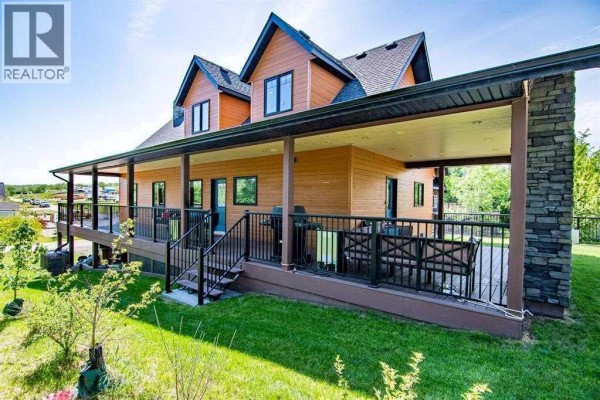 Snow-covered property with a large deck, overlooking a frozen lake and wooded area. - 2 Sunset Lane, Rural Stettler No  6, County Of