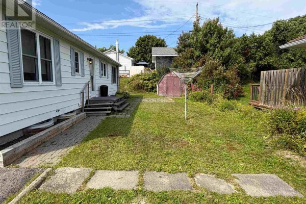 Backyard of the bungalow with a clothesline, shed, and wooden fence. - 2 Tecumseh Rd, Elliot Lake