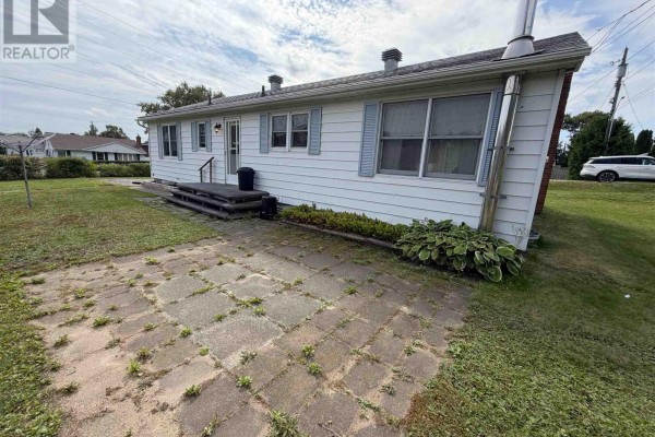 Side exterior of the bungalow with a flagstone patio and green lawn. - 2 Tecumseh Rd, Elliot Lake