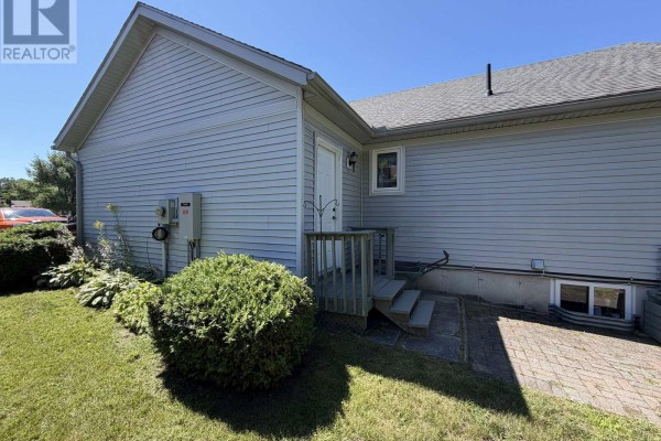 Side exterior of house showing light blue siding, wooden deck stairs, and a basement window. - 2 Twigs End, Gravenhurst)