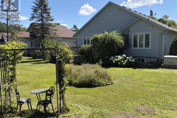 Side view of the house with a large green lawn, metal pergola with seating, and a generator. - 2 Twigs End, Gravenhurst)