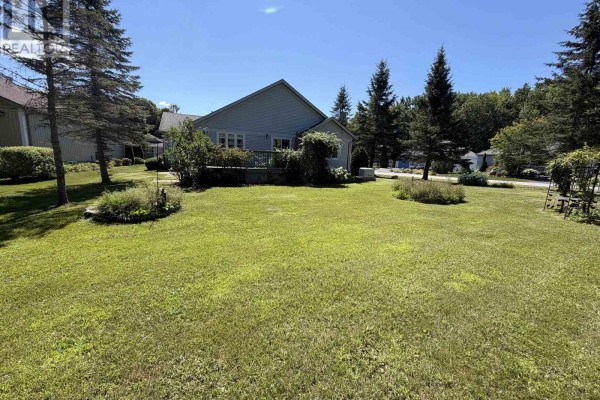 Expansive green lawn with mature trees and bushes surrounding the rear and side of the house. - 2 Twigs End, Gravenhurst)