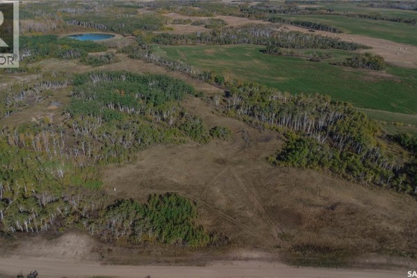 Aerial view of a large parcel of land featuring mixed trees, open grassy areas, and a distant pond. - 2 Whitetail Trail, Duck Lake Rm No  463