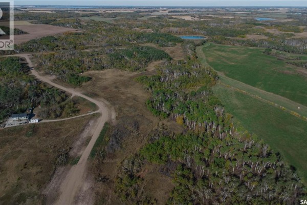 Aerial view showing a rural property entrance with a sign, trees, and fields with a small building. - 2 Whitetail Trail, Duck Lake Rm No  463